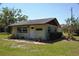 Cute bungalow with a white exterior, green lawn, and mature trees at 1879 Lake Emma Rd, Longwood, FL 32750