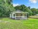 White house with a porch and green lawn at 5136 Mcdonald Rd, Zellwood, FL 32798