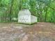 White shed with double doors situated in a wooded backyard at 5136 Mcdonald Rd, Zellwood, FL 32798