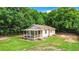 White house with a large front porch, surrounded by lush green trees at 5136 Mcdonald Rd, Zellwood, FL 32798