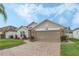 Exterior view of a tan house with a two-car garage and landscaped yard at 442 Ella Mae Dr, Davenport, FL 33897