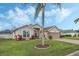 Exterior of a house with a palm tree, landscaping, and two-car garage at 442 Ella Mae Dr, Davenport, FL 33897