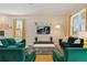 Living room with green velvet sofas, large TV, and yellow accents at 8834 Cabot Cliffs Dr, Davenport, FL 33896