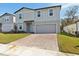 Two-story house with gray siding, brick driveway, and landscaped lawn at 28046 Poppy Ct, Leesburg, FL 34748