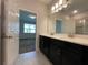 Double vanity bathroom with dark cabinets and a view of a bedroom at 14154 Dove Hollow Dr, Orlando, FL 32824