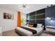 Modern bedroom with a gray platform bed, orange curtains, and a geometric wall at 2726 Oxymoron Way, Kissimmee, FL 34746