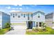 Two-story light blue house with a two car garage and landscaped front yard at 3020 Mahalo Dr, Davenport, FL 33897