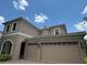 Two-story house with beige exterior, three-car garage, and a paver driveway at 2211 Rickover Pl, Winter Garden, FL 34787