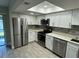 Modern kitchen with white cabinets, stainless steel appliances, and gray tile flooring at 6003 Village Cir # Ge, Orlando, FL 32822