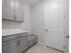 Bright laundry room with gray cabinets, countertop, and built-in bench at 3860 Rose Malllow Dr, Kissimmee, FL 34746