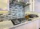 Modern gas cooktop with granite countertops and backsplash at 15680 Panther Lake Dr, Winter Garden, FL 34787