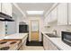 Galley kitchen with white cabinets, stove, and microwave at 1000 S Orlando Ave # A5, Maitland, FL 32751