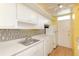 Bright kitchen features white cabinets, metal backsplash, and modern appliances at 700 Melrose Ave # E4, Winter Park, FL 32789