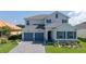 Two-story house with gray double garage doors and stone accents at 30053 Island Club Dr, Tavares, FL 32778