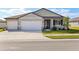 Two-car garage, light grey exterior, and a well-manicured lawn at 2012 Rosewood Dr, Bartow, FL 33830