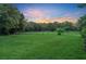 Spacious grassy backyard with trees and sunset at 1709 Onondaga Dr, Geneva, FL 32732