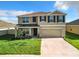 Two-story house with tan siding, dark shutters, and a two-car garage at 5043 Sw 88Th Pl, Ocala, FL 34476