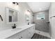Double vanity bathroom with gray tile shower and white cabinets at 43 S Kentucky Ave, Umatilla, FL 32784