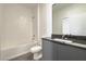 Clean bathroom with white tiled shower, gray vanity, and dark countertop at 3229 Energy Dr, Kissimmee, FL 34747
