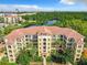 Aerial view of a multi-story building with tile roofs, lush landscaping, and a lake nearby at 8801 Worldquest Blvd # 4406, Orlando, FL 32821