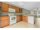 Bright kitchen with wood cabinets, white appliances, and tile flooring at 3651 N Goldenrod Rd # B107, Winter Park, FL 32792