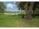 Serene lake view with a chair under a large oak tree at 3355 Scarlet Dr, Sanford, FL 32773
