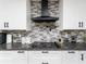 Modern kitchen with sleek black range hood and gray stone backsplash at 3355 Scarlet Dr, Sanford, FL 32773