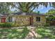 Stone house exterior with red door, landscaping, and large oak tree at 3355 Scarlet Dr, Sanford, FL 32773