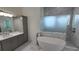 Elegant bathroom with soaking tub, walk-in shower, and gray cabinets at 555 Sanctuary Golf Pl, Apopka, FL 32712