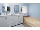 Bathroom with double vanity, light gray cabinets, and a beige bathtub at 550 Saint Johns Rd, Tavares, FL 32778