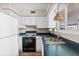 Kitchen with white cabinets, black appliances, and a dark countertop at 335 N Causeway # B010, New Smyrna Beach, FL 32169