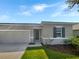 Two-car garage, gray exterior, and nicely landscaped yard at 273 Summershore Dr, Auburndale, FL 33823