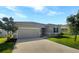 Two-car garage, gray exterior, and well-maintained lawn at 273 Summershore Dr, Auburndale, FL 33823