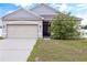 One-story home with gray siding, dark garage door, and landscaping at 1100 James Way, Kissimmee, FL 34759