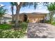 Tan one-story house with a two-car garage and well-manicured lawn at 619 Kensington Dr, Davenport, FL 33897