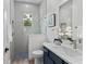 Modern bathroom with gray tile, a walk-in shower, and a navy blue vanity at 3429 Boggy Creek Rd, Kissimmee, FL 34744