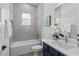 Clean bathroom featuring a bathtub, gray tile, and a navy blue vanity at 3429 Boggy Creek Rd, Kissimmee, FL 34744