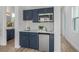 Small, modern kitchenette with navy blue cabinets and stainless steel appliances at 3429 Boggy Creek Rd, Kissimmee, FL 34744