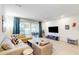 Bright living room featuring a sectional sofa, large TV, and access to a private pool at 17317 Hidden Forest Dr, Clermont, FL 34714