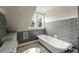 Updated bathroom with gray tile, white bathtub, and window at 1689 Lakeshore Dr, Eustis, FL 32726