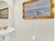 Elegant powder room with pedestal sink, framed art, and gold accents at 7706 Graben St, Kissimmee, FL 34747