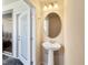Small, well-appointed powder room with pedestal sink and oval mirror at 7143 Oakmoss Loop, Davenport, FL 33837