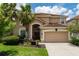 Two-story house with tan exterior, brown roof, and a two-car garage at 5237 Oakbourne Ave, Davenport, FL 33837