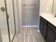 Main bathroom with shower, double vanity, and light grey wood-look flooring at 8073 Cherrystone St, Leesburg, FL 34748