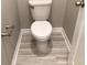 Small bathroom with toilet and light grey wood-look flooring at 8073 Cherrystone St, Leesburg, FL 34748