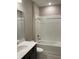Bathroom with tub, single vanity, and white tiled walls at 8073 Cherrystone St, Leesburg, FL 34748