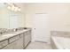 Bathroom with double vanity, granite countertop and large mirror at 7252 Oakmoss Loop, Davenport, FL 33837