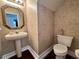 Small bathroom with pedestal sink, toilet, and textured wallpaper at 1817 Baillie Glass Ln, Orlando, FL 32835