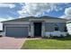 One-story home with gray exterior, brick paver driveway and landscaping at 6821 Serpent Hawk Lane St, Howey In The Hills, FL 34737