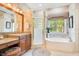 Spa-like bathroom with granite double vanity, a soaking tub, and a walk-in shower at 1650 Lakehurst Ave, Winter Park, FL 32789